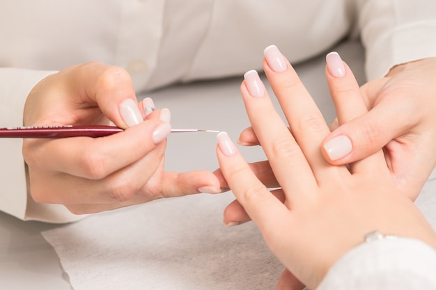 Woman receiving french manicure by beautician