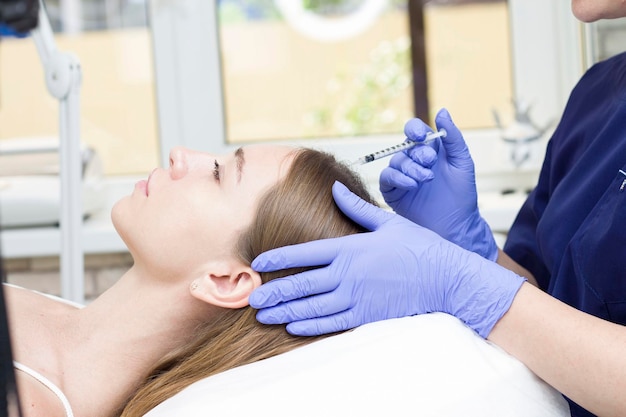 A woman receiving an injection into the scalp at a beauty center