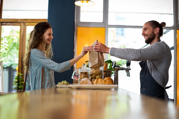 Woman receiving parcel from waiter at counter