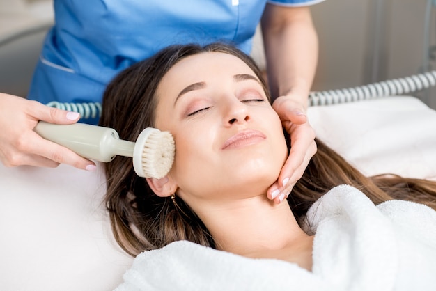 Woman receiving professional brush peeling in the cosmetology office