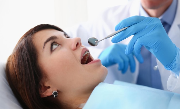 A woman at the reception of a male dentist examining teeth and oral cavity