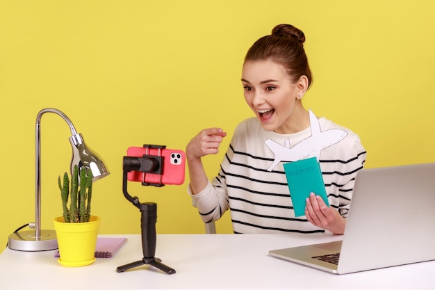 Woman recording video to followers showing passport and paper plane boasting her tour for vocation