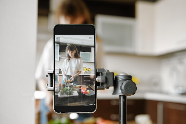 Photo woman recording video recipe while cooking in the kitchen