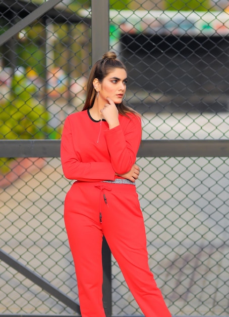 Photo a woman in a red jumpsuit stands in front of a fence