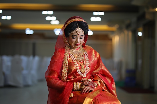 a woman in a red sari sits in a room with other people