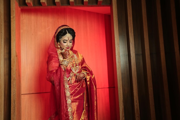 a woman in a red sari stands in front of a red curtain