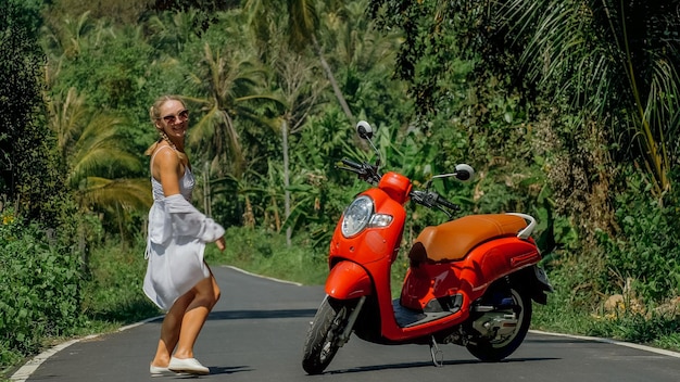 Woman on red scooter in white clothes drive on forest road trail Dancing trip One girl caucasian