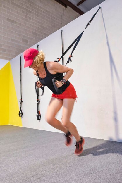 Photo a woman in a red shirt and black tank top is exercising she is holding onto a tax rope