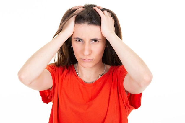 Woman in red shirt in pain having headache two hands on head