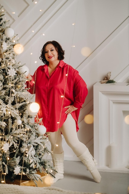 A woman in a red shirt in a room near a Christmas tree decorated for Christmas Home New Year atmosphere