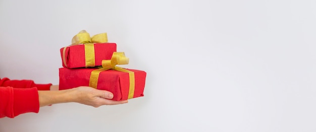 A woman in a red sweater holds a red Christmas present on a white background. Gift concept for Christmas and New Year.