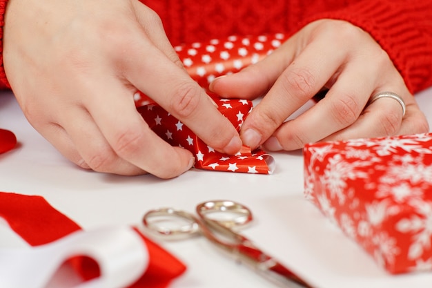 Woman in red sweater wrapping present in a red paper