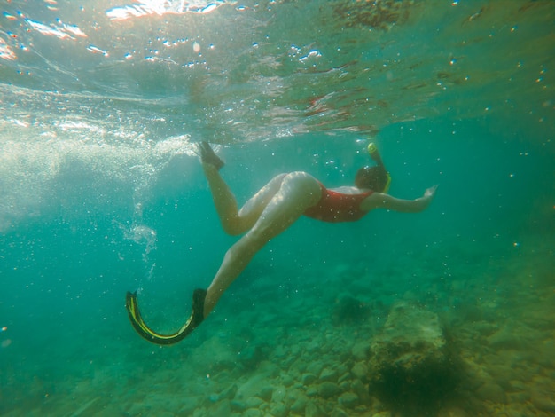 Woman in red swimming suit underwater with snorkeling mask and flippers