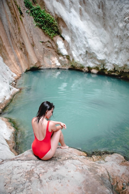 Woman in red swimsuit Dimosari waterfall at Lefkada island Greece