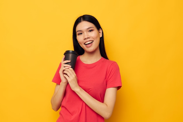 Woman in a red tshirt glass with a drink yellow background