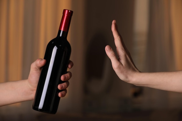 Woman refusing to drink red wine indoors closeup Alcohol addiction treatment