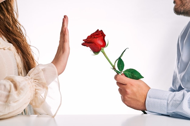 Woman rejecting a rose from her partner. Concept of breakup, rejection and lack of love.