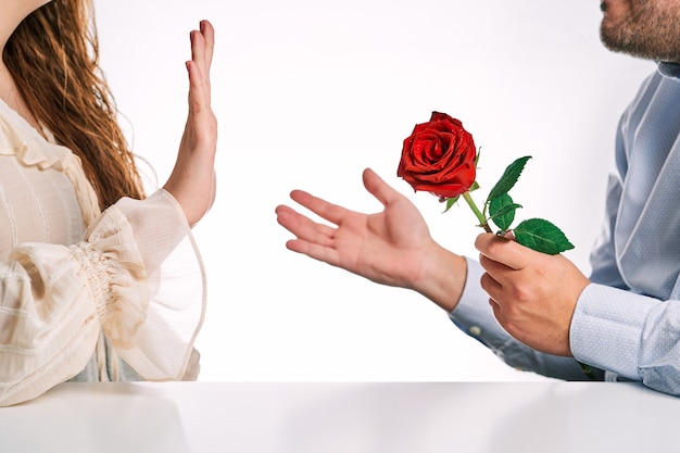 Woman rejecting a rose from her partner. Concept of breakup, rejection and lack of love.