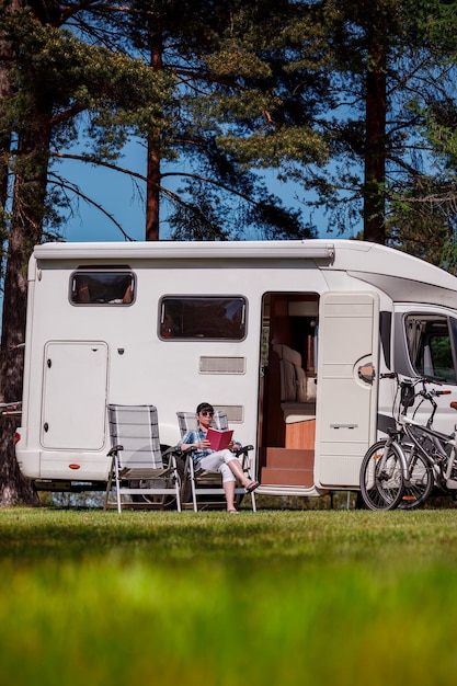 Woman relaxes and reads a book near the camping . Caravan car Vacation. Family vacation travel, holiday trip in motorhome RV.