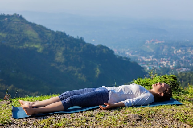 Woman relaxes in yoga asana Savasana outdoors