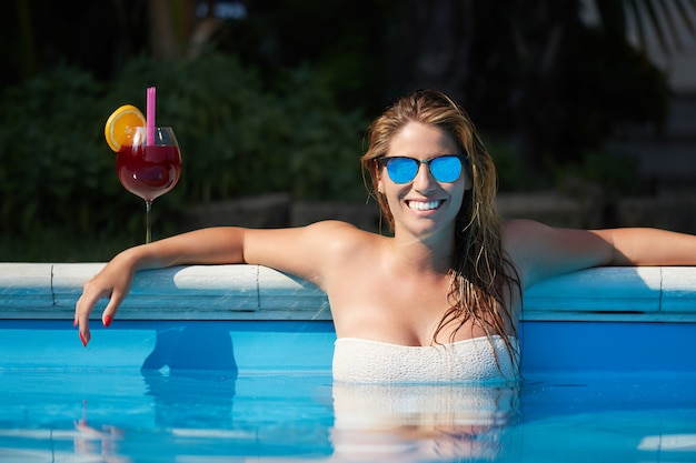 Woman relaxing and drink a cocktail at swimming pool