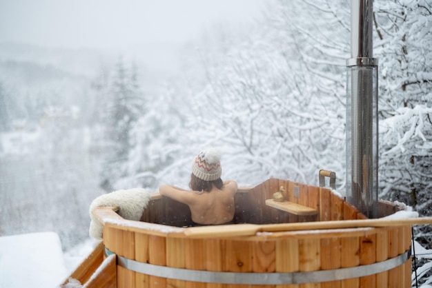 Woman relaxing in hot bath at snowy mountains