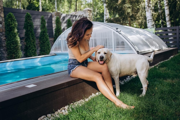 Woman relaxing near swimming pool with cute dog