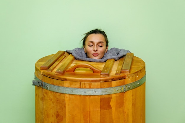 Woman relaxing in spa wooden hot tub, barrel sauna or cedar bathtub