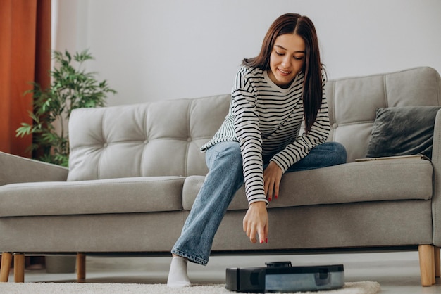 Photo woman relaxing while robot vacuum cleaner cleaning up the room