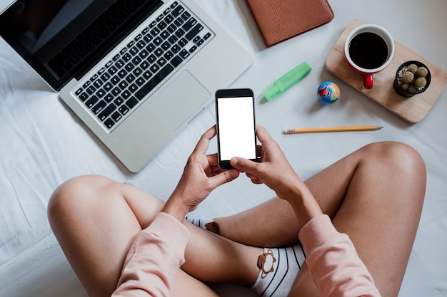 Woman relaxing while using smartphone blank screen for graphics display montage. view frome above