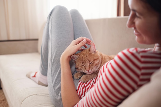 Woman relaxing with her ginger pet on a sofa Cosy scene hygge concept