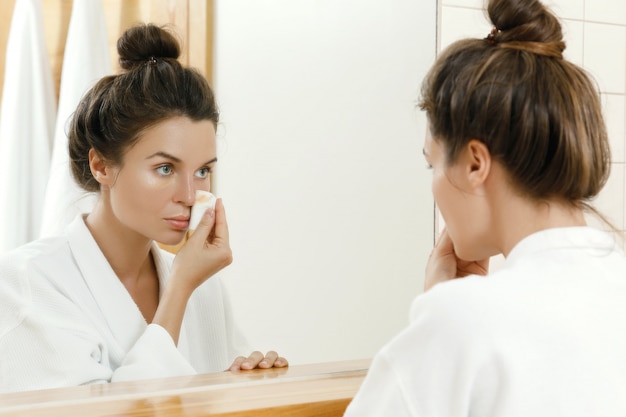 Woman removing makeup with a cotton pad