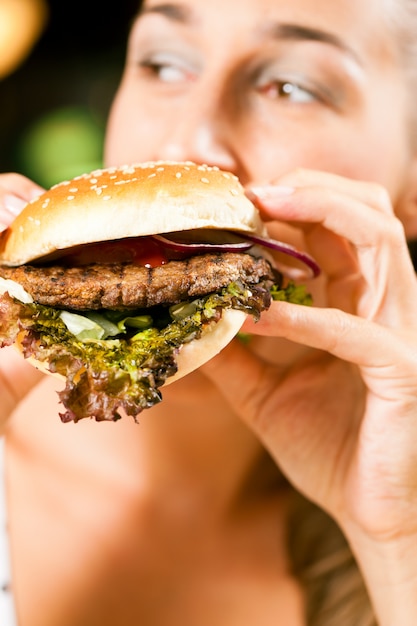 Woman in a restaurant eating hamburger