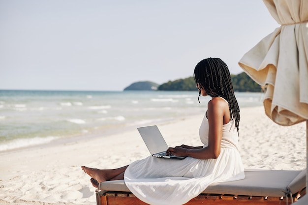 Woman resting on beach with laptop