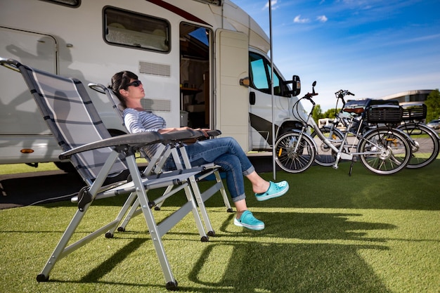 Woman resting on a camping chair on the nature. Caravan car Vacation. Family vacation travel, holiday trip in motorhome