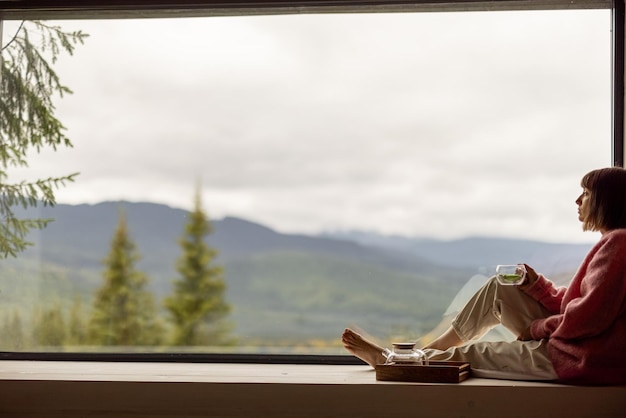 Woman rests in house with scenic views in mountains