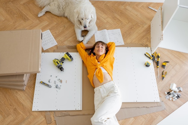 Woman rests with her cute dog while making repairing at new apartment