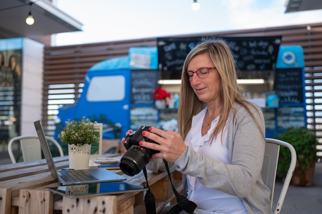 Woman reviewing photographs on a reflex camera in a coffee shop