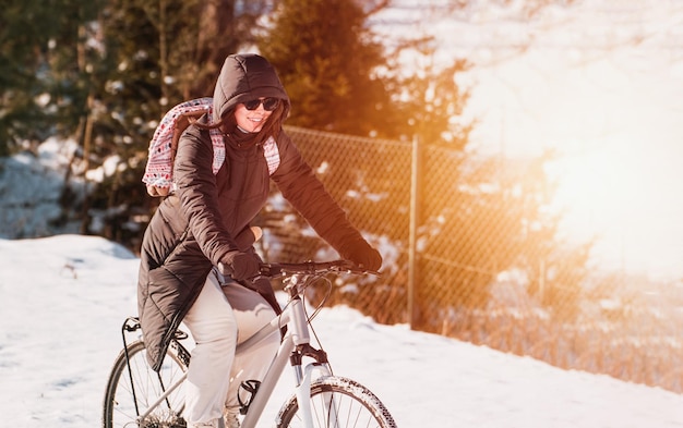 Woman rides bicycle in winter snow