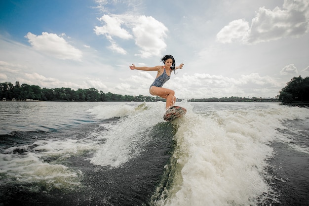 Photo woman riding stylish pink wakeboard on high wave