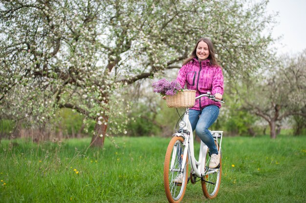 Woman riding a vintage white bicycle with flowers in basket