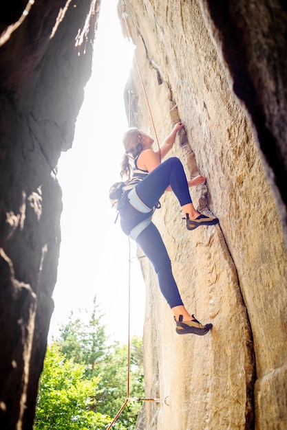 Woman rock climbing with rope on a steep rock wall