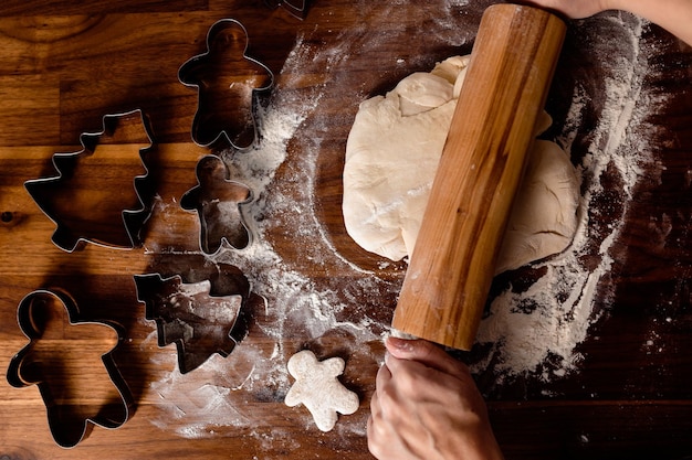 Woman roll out the dough. Ginger coockies on wooden table. Cozy home cooking. Home baking.