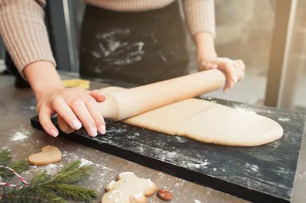 Woman rolling out dough at kitchen