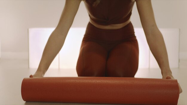 Woman rolling out yoga mat before training Girl preparing equipment for yoga