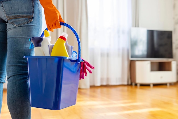 Woman in rubber gloves with bucket of cleaning supplies ready to clean up