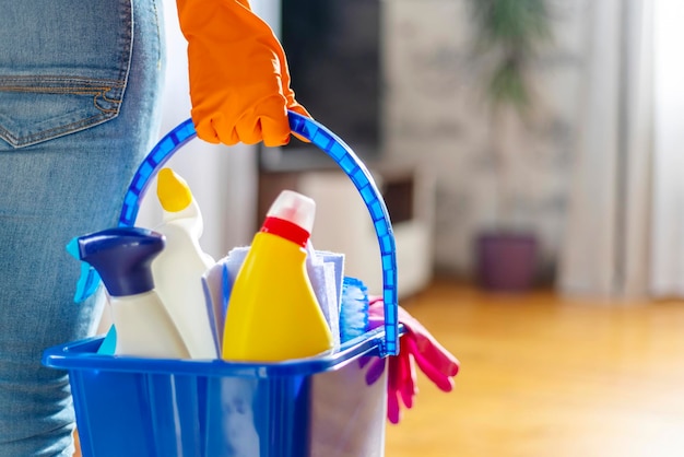 Woman in rubber gloves with bucket of cleaning supplies ready to clean up