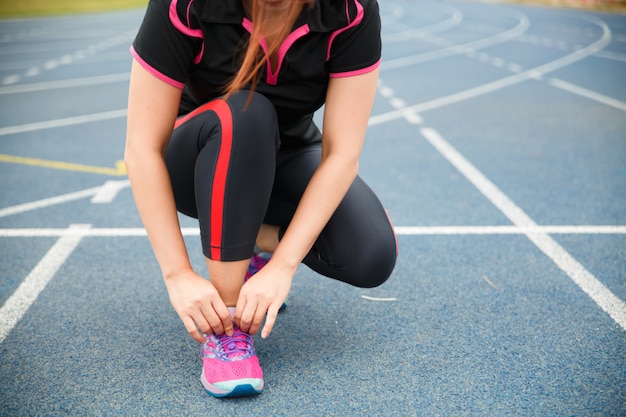 Woman runner tying running shoes before run for exercise in the morning. Woman runner checking shoe in order to get ready to run.