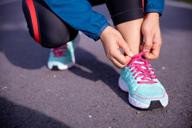 Woman runner tying running shoes before run for exercise in the morning