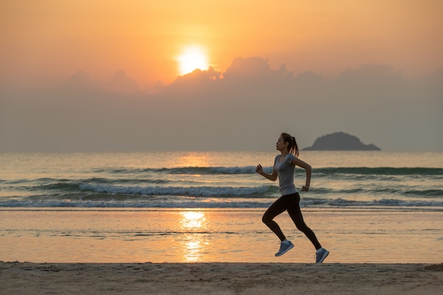 Woman running on beach at sunrise